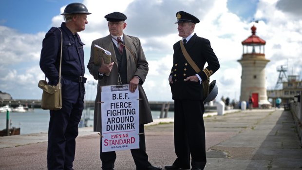 Men dressed as a 1940s newspaper vendor, an air raid warden and a member of the Royal Navy stand on the harbour wall in Ramsgate, England. 