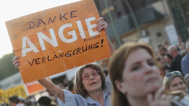 A supporter of the German Christian Democrats holds up a sign that reads: "Thanks Angie, keep going!" in reference to German Chancellor Angela Merkel.