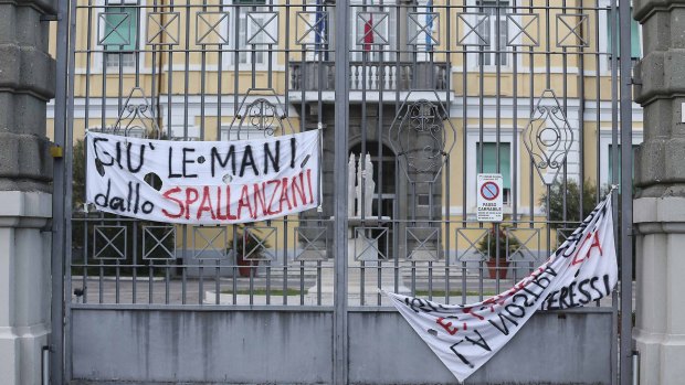 A banner reads "Hands off from the Spallanzani" on the gate of the infectious diseases institute in Rome.