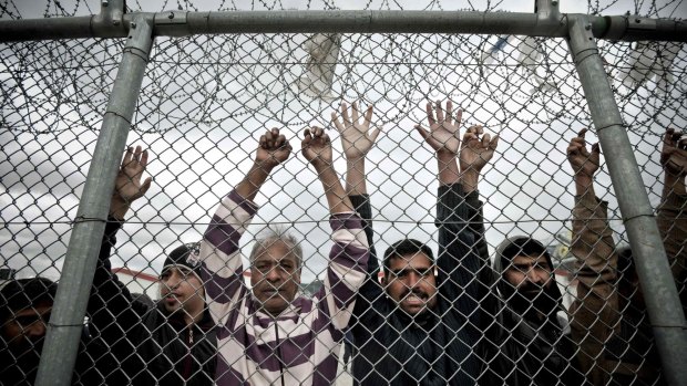 Immigrants stand behind a fence at the Amygdaleza detention centre in western Athens on February 14.  