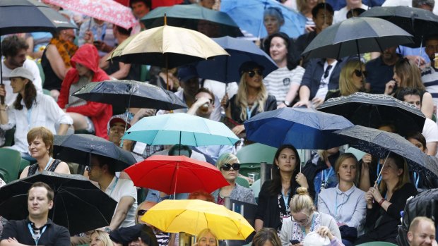 Rain-soaked spectators wait for the Rod Laver roof to close on Friday. 