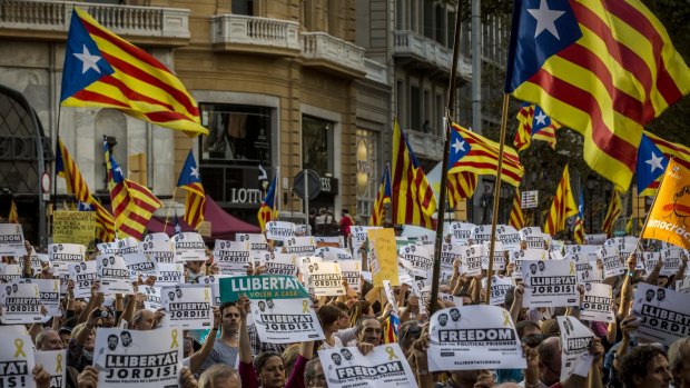 Protesters wave Catalan flags and hold signs during a demonstration against the Spanish government.