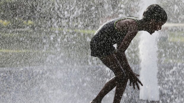 An Indian child bathes under a public  fountain on a hot afternoon in Lucknow.