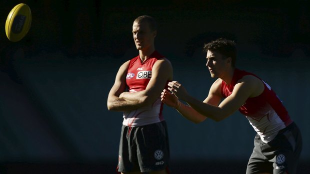 Sibling rivalry: Xavier Richards handballs at Swans training while brother Ted looks on.
