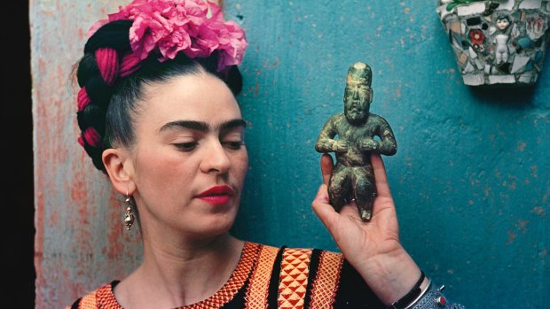 Frida Kahlo with Olmec figurine, cira 1939. Photograph by Nickolas Muray.