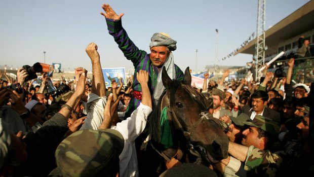 Then Afghan presidential candidate Abdul Rashid Dostum waves to supporters at a campaign rally in Kabul in 2004.