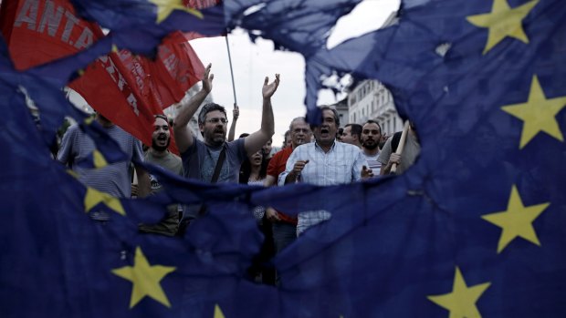 Protesters are seen through a burned European Union (EU) flag during an anti-austerity demonstration in Greece last year. 