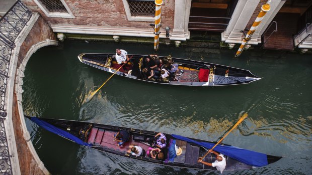 Gondoliers in a canal, Venice, Italy.