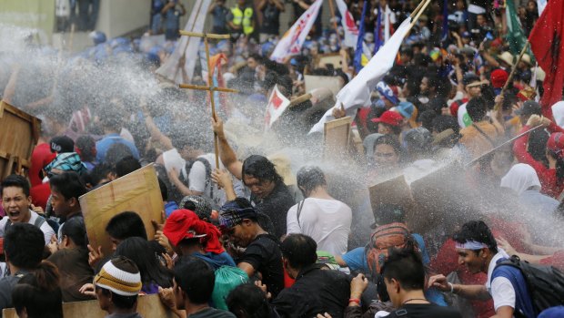 Student activists bear the brunt of police water cannons as they protest near the venue hosting the  APEC summit in Manila.