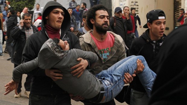 Anti-government protesters help an injured man after being attacked by pro-government protesters during a demonstration in front of the press syndicate in Cairo on Sunday. Over 25 were killed in the clashes.