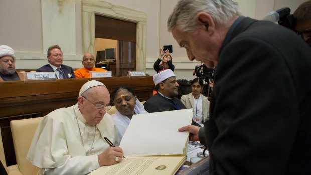 Signing up: Pope Francis signs a joint Declaration of Religious Leaders against Modern Slavery as Andrew Forrest watches on.