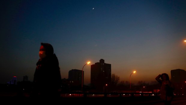 A star is twinkling above a pedestrian wearing a mask silhouetted against the city skyline shrouded in heavy smog in Beijing on Monday.