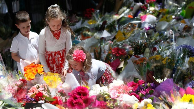 A girl adds flowers to the tributes at Martin Place.