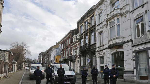 Belgian police arrested 13 people during a dozen raids overnight. Here police officers guard a street in Verviers, Belgium.