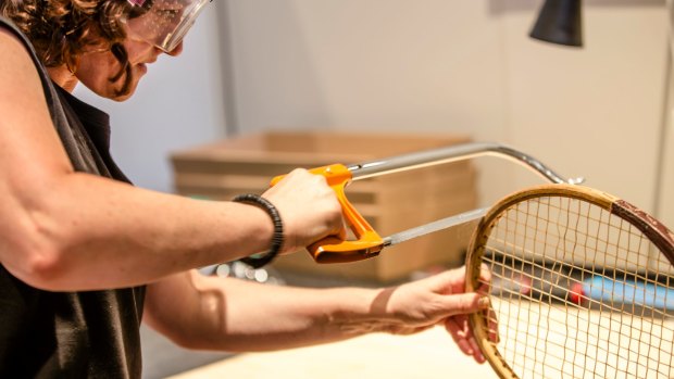 A participant saws apart a tennis racket.
