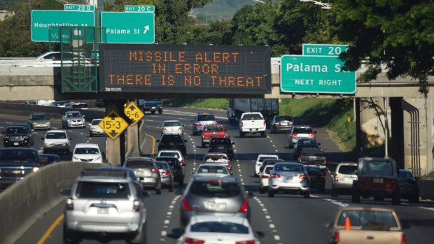 Cars drive past a highway sign that says "MISSILE ALERT ERROR THERE IS NO THREAT" on the H-1 Freeway in Honolulu on the weekend.