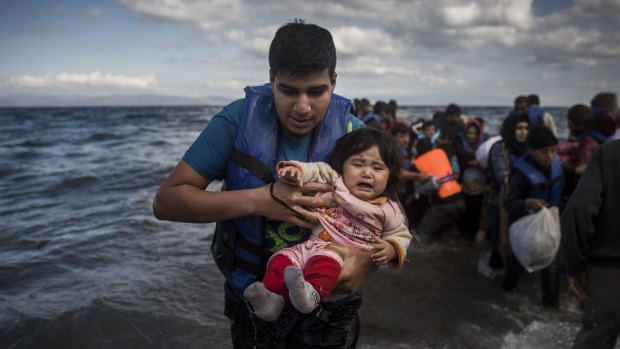 A man and a baby disembark from a dinghy after travelling from the Turkish coast to the north-eastern Greek island of Lesbos.