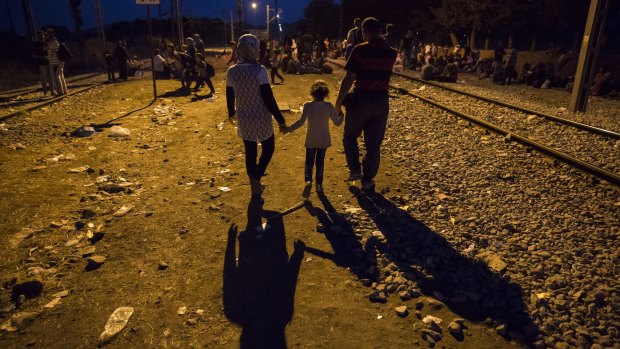 A family walks along the train tracks at dusk at the Greek Macedonian border  in Idomeni, Greece. 