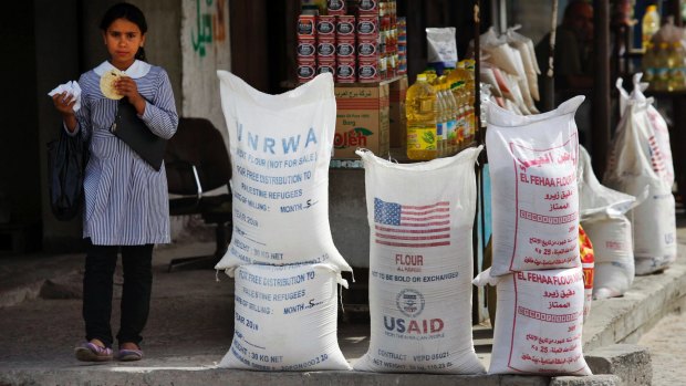 A Palestinian pupil walks past sacks of flour, some part of humanitarian aid by United Nations Relief and Works Agency.