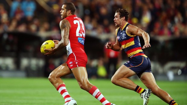 Lance Franklin of the Swans is pursued by Kyle Hartigan of the Crows as he moves upfield.