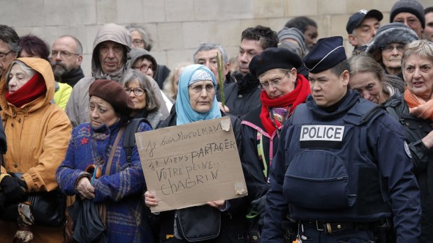 A woman holds a board reading: " I am muslim, I am here to share your pain" as she waits to enter at the Pere Lachaise cemetery during the funeral of cartoonist Bernard Verlhac in Paris.