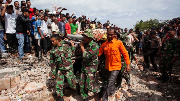Military personnel and aid workers carry out victims of the Aceh earthquake in Pidie Jaya.