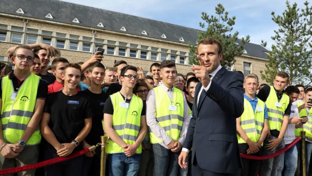 French President Emmanuel Macron stands alongside students during a visit to EATP, which is devoted to apprenticeship and vocational training, in Egletons, central France.