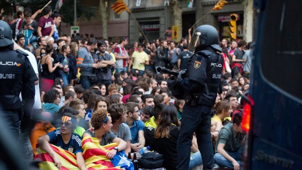 A Spanish national police officer stands guard outside the offices of the left-wing party CUP in Barcelona. Police left after waiting for hours for permission to search the premises for referendum-related propaganda that never arrived.  