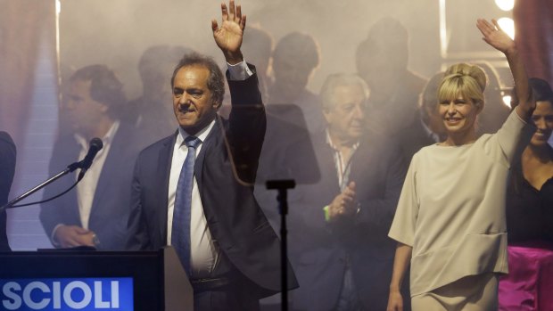 Buenos Aires' Governor and ruling party presidential candidate Daniel Scioli, left, waves to supporters, next to his wife Karina Rabolini, right, as they wait for results of Sunday's poll in Buenos Aires, Argentina.