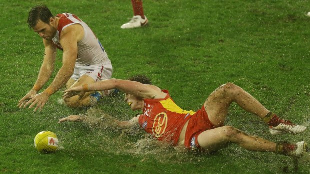 Slippery conditions: Ben McGlynn and Jesse Joyce compete for the ball during the round 11 AFL match between the Gold Coast Suns and the Sydney Swans at Metricon Stadium.