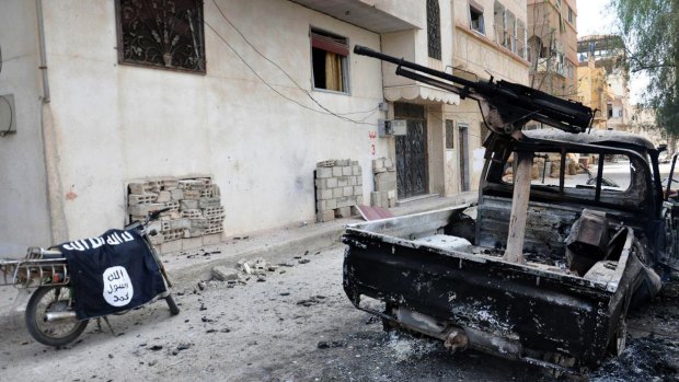 A burned vehicle with machine gun is seen next to a motorcycle draped with the Islamic State flag in Palmyra.