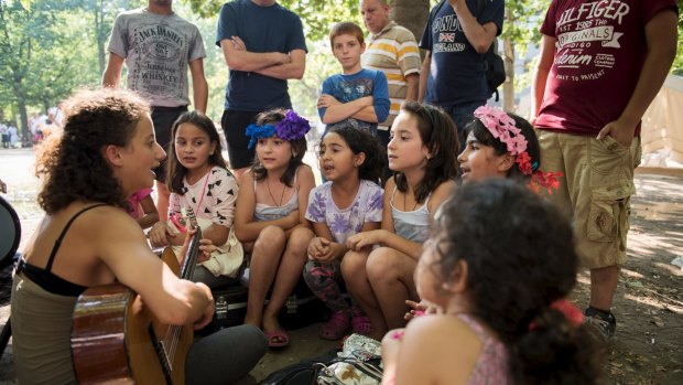 Volunteers sing with migrant children in front of the Berlin State Office for Health and Social Affairs where they wait with other migrants to apply for asylum.