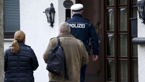 A German police officer and unidentified people prepare to enter a house believed to belong to crashed Germanwings flight 4U 9524 co-pilot Andreas Lubitz in Montabaur, Germany