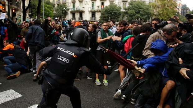 A Spanish National Police officer clashes with pro-referendum supporters in Barcelona on Sunday.