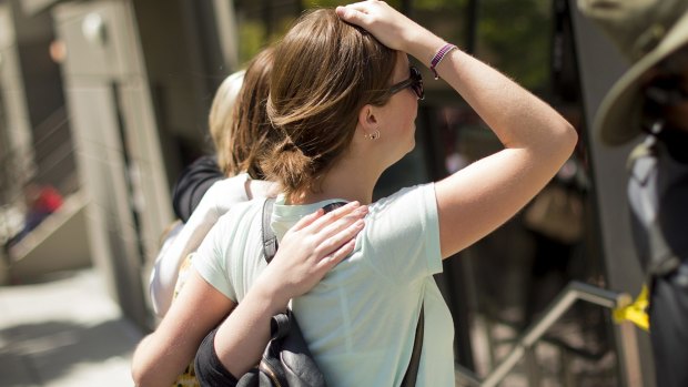 Women embrace after leaving flowers at the site of a balcony collapse.