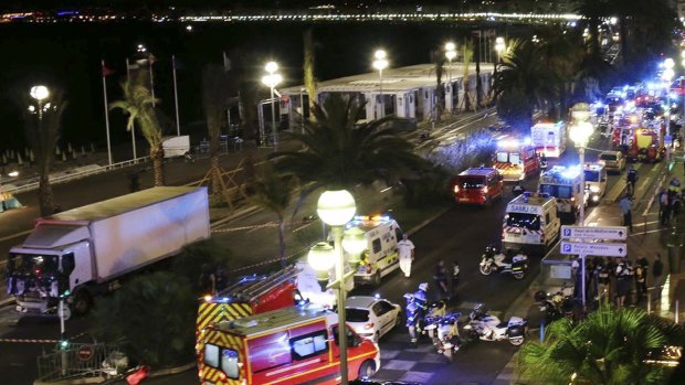 Emergency services vehicles work on the scene after a truck, left, plowed through Bastille Day revellers in the French resort city of Nice, France.