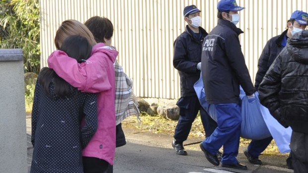 Police officers carry a dead body past the relatives after the body was found at a site collapsed by an earthquake in Mashiki, Kumamoto prefecture, on Saturday. 