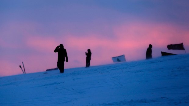People walk along a snowy hillside at the Oceti Sakowin camp where crowds gathered to protest the Dakota Access oil pipeline.