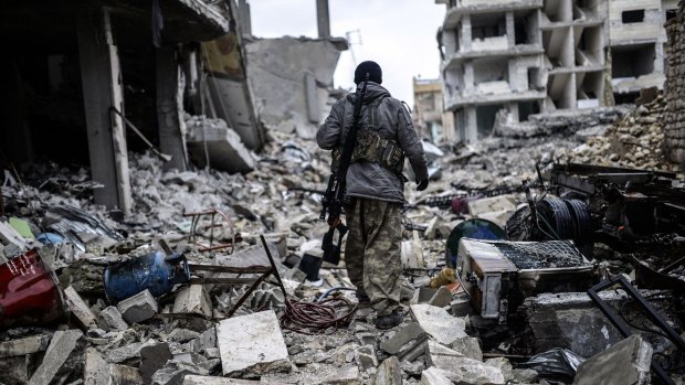 Musa, a 25-year-old Kurdish sniper, walks in the rubble of the Syrian town of Kobane, also known as Ain al-Arab.