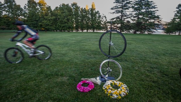 A cyclist passes the memorial to British endurance cyclist Mike Hall in Nara Park, where a memorial was held early Friday morning.