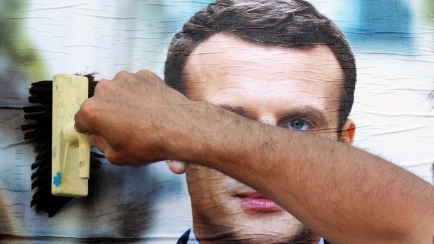 A supporter of French centrist presidential candidate Emmanuel Macron glues a campaign poster in Bayonne, south-western France.