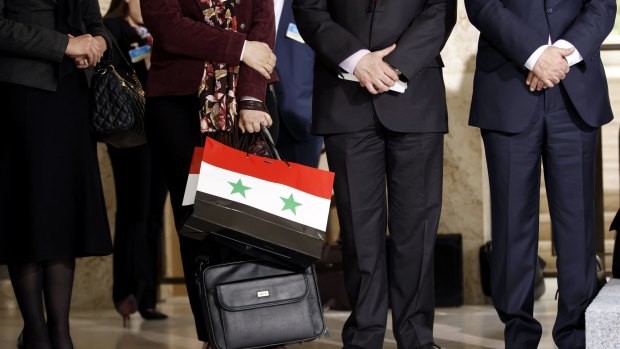 A member of the Syrian government holds a bag with the colours of the Syrian flag at a press conference in Geneva on Monday. 