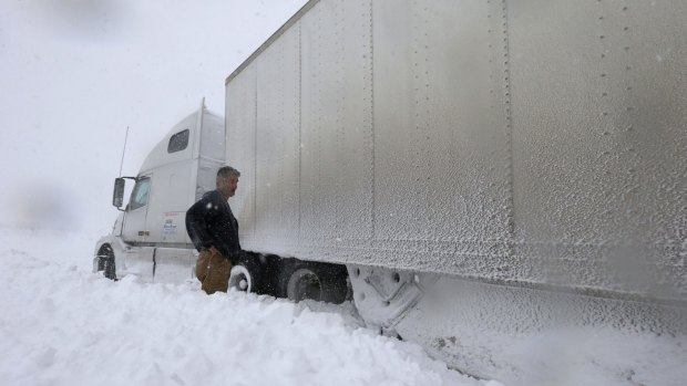 A truck driver looks at his trapped vehicle in Boston, New York.