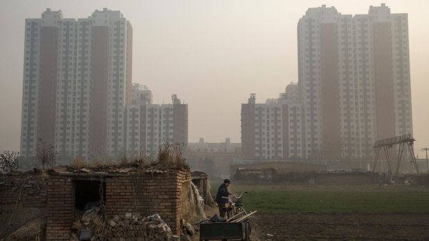 An elderly Chinese farmer stands outside her home near a housing development in Hebei province just outside Beijing.