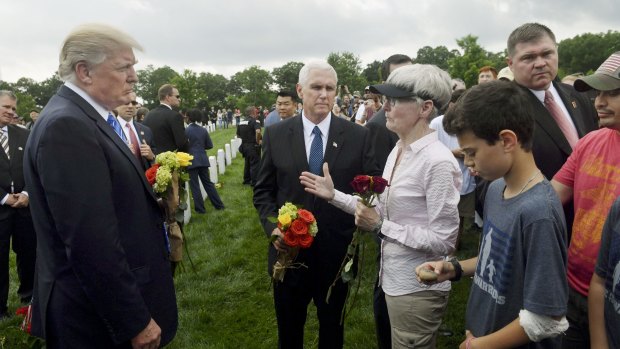 Donald Trump and Vice-President Mike Pence, centre, speak with attendees at Arlington National Cemetery on Monday.