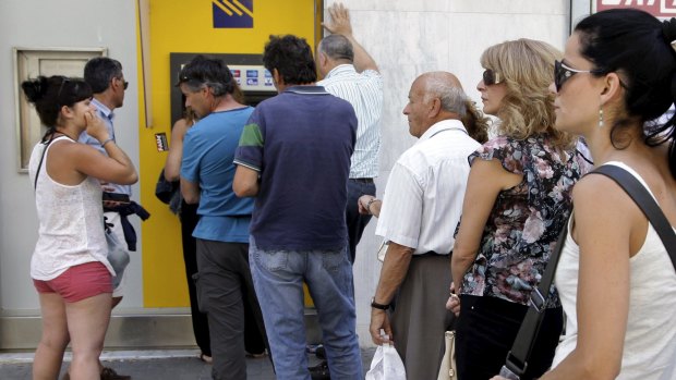 People line up to withdraw cash from an automated teller machine on the island of Crete.
