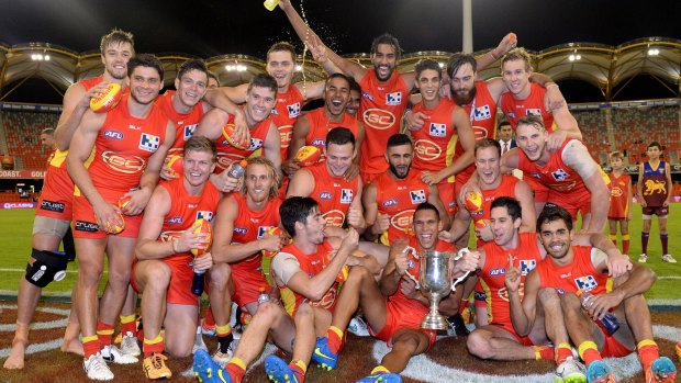 Gold Coast Suns players celebrate their victory over the Brisbane Lions.