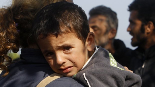 A boy on his mother's shoulder as they enter into Macedonia from Greece on the border  between the two countries on Tuesday. 