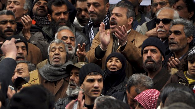 Palestinian residents of the Yarmouk refugee camp take part in a protest expressing their determination to stay inside the camp on Sunday.