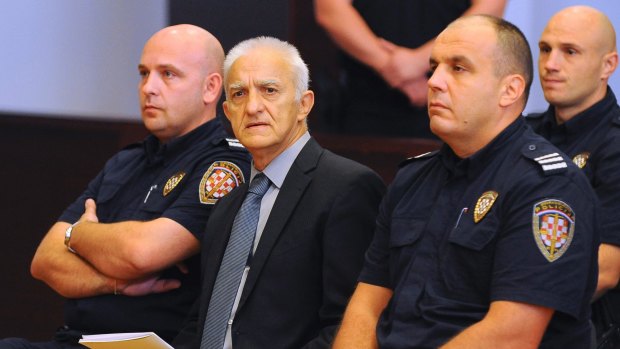 Dragan Vasiljkovic sits between two guards in a courtroom at the beginning of his trial in Split, Croatia.
